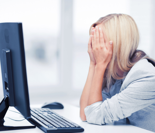 Frustrated woman hiding face in hands in front of screen