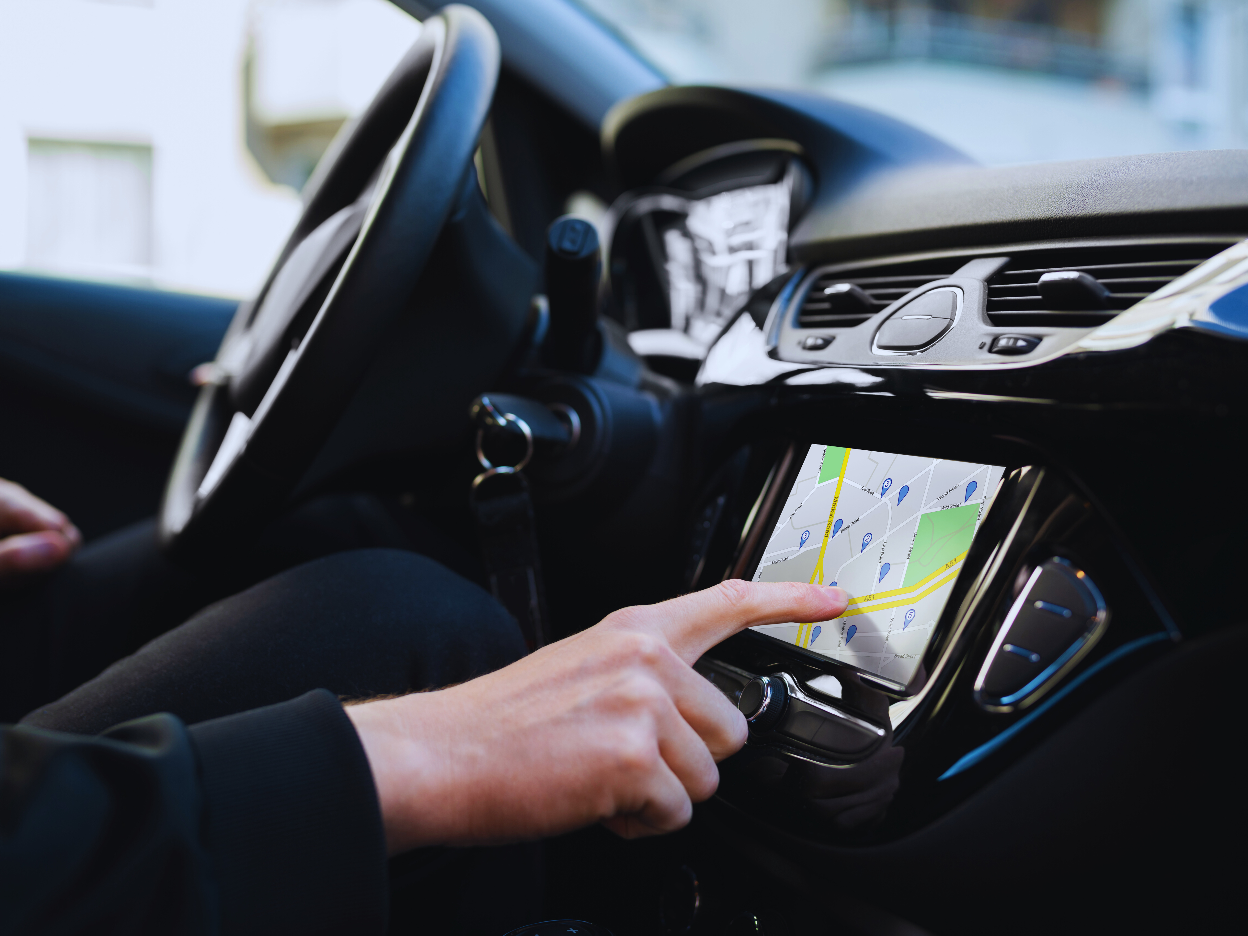 Car infotainment system with person clicking on GPS with finger while driving