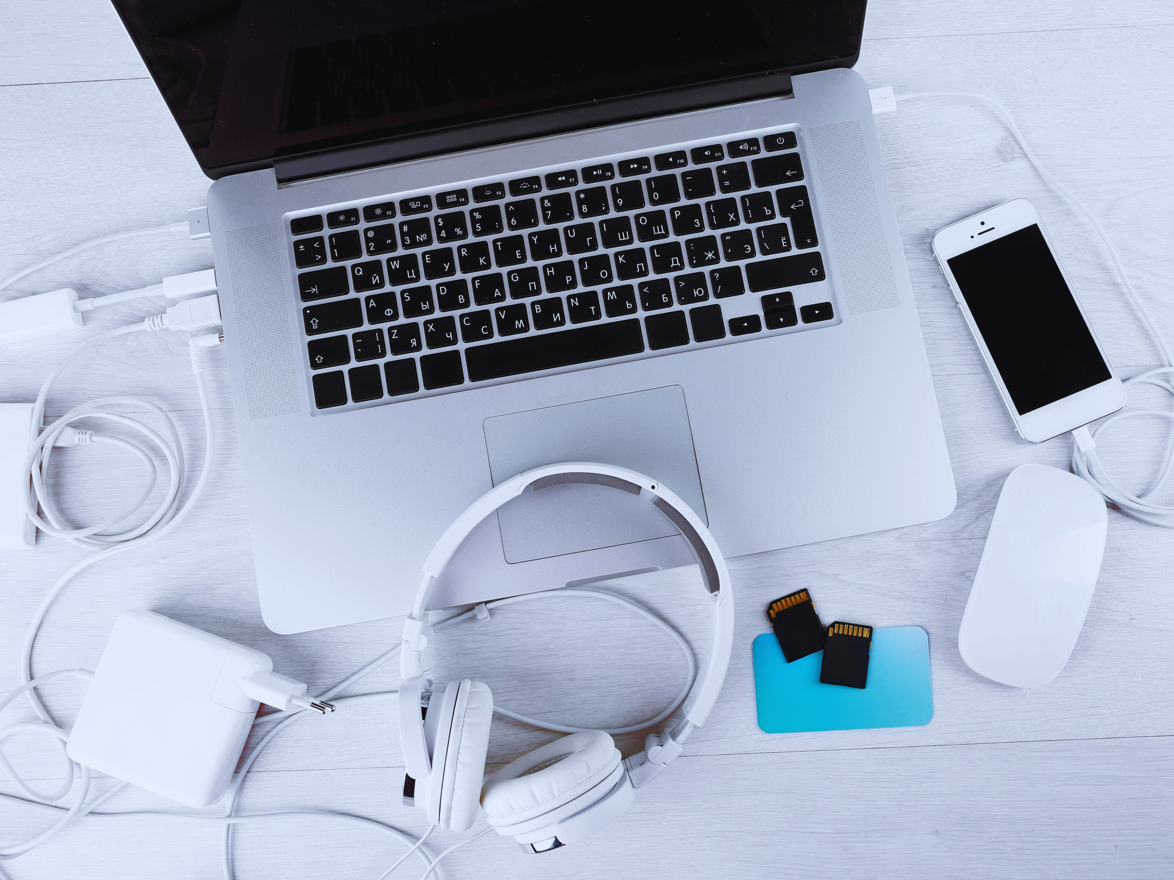 1. A laptop, headphones, and various electronic devices arranged on a wooden table.