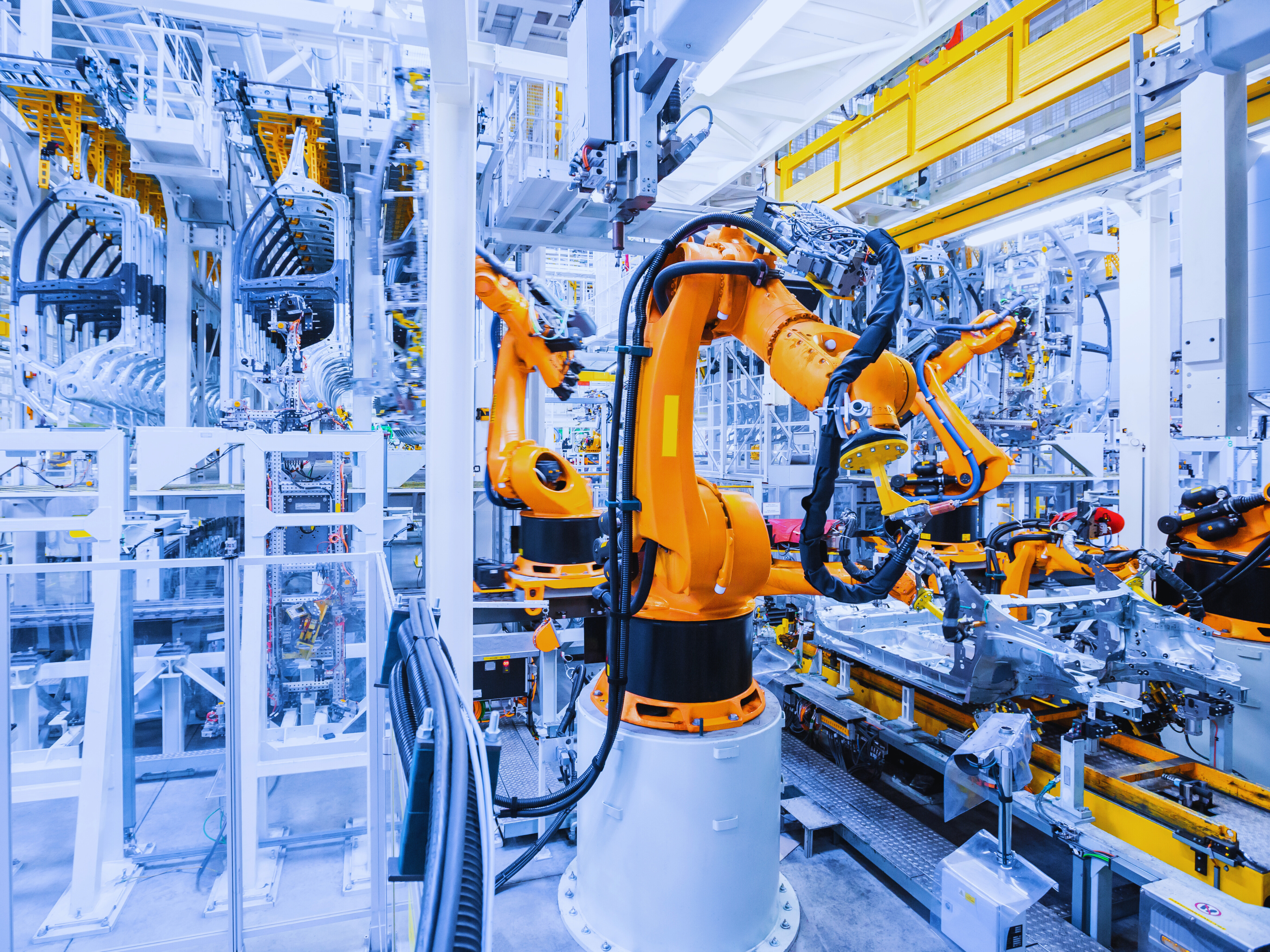 1. Robots operate among various machines in a busy factory setting, showcasing automation in manufacturing processes.