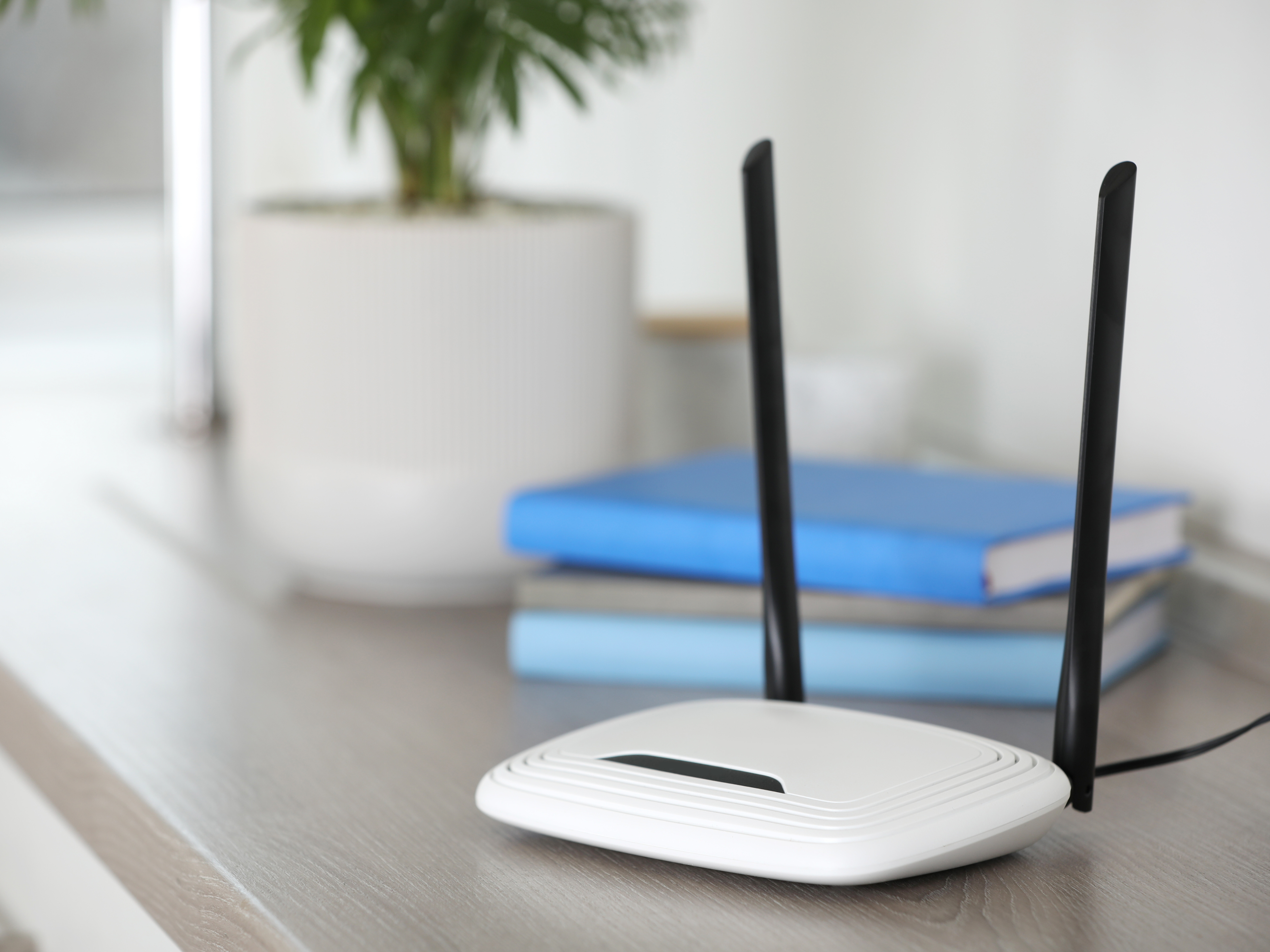 Wifi router on table with plant and books in background