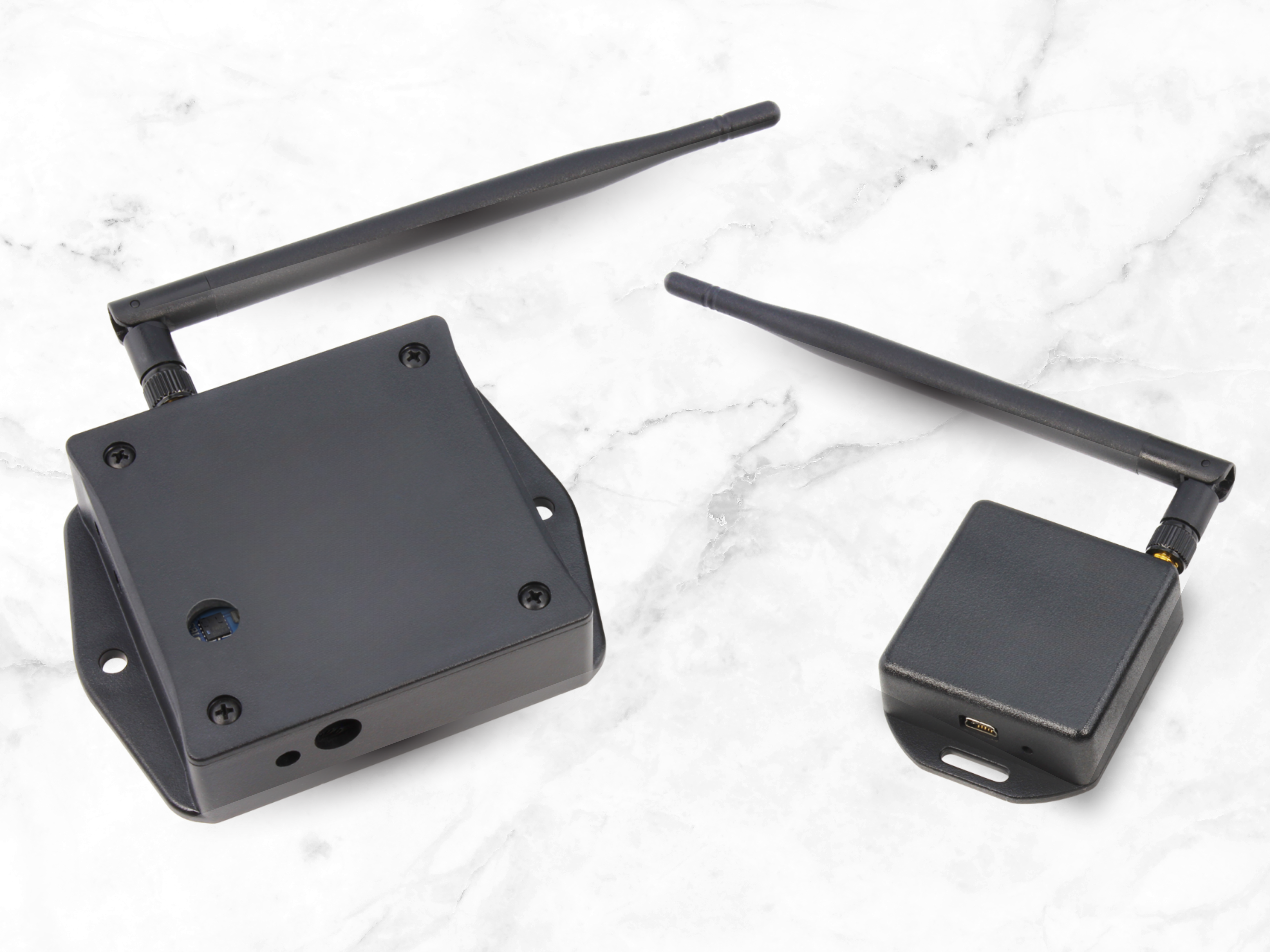 Two black wireless IoT devices resting on a polished marble surface.